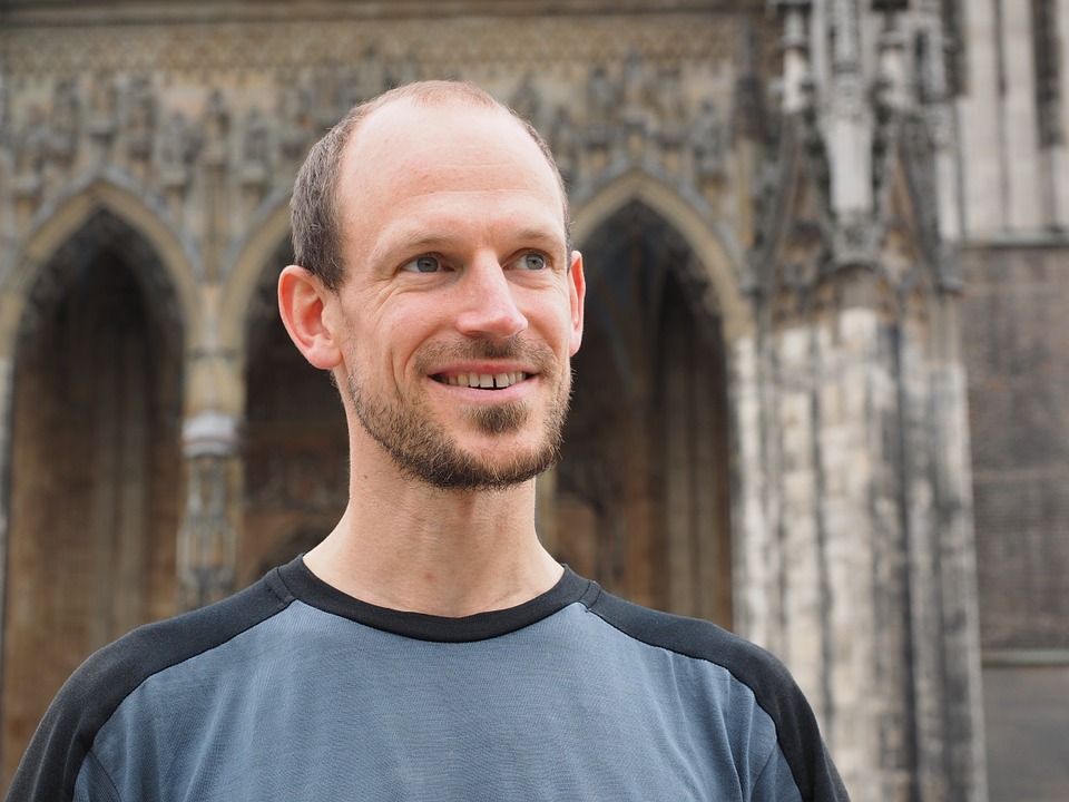 Smiling headshot of a man in black and gray tshirt